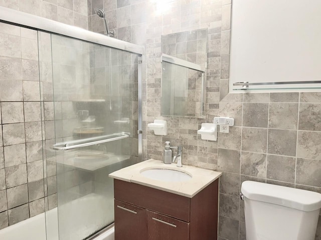 full bath with enclosed tub / shower combo, toilet, tile walls, and vanity