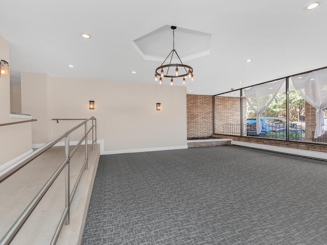 corridor featuring carpet floors, an inviting chandelier, recessed lighting, expansive windows, and a raised ceiling