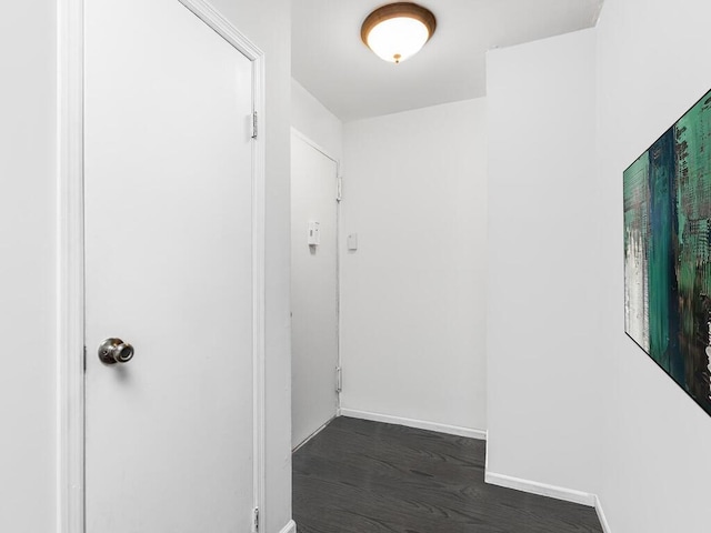 hallway with dark wood-type flooring and baseboards