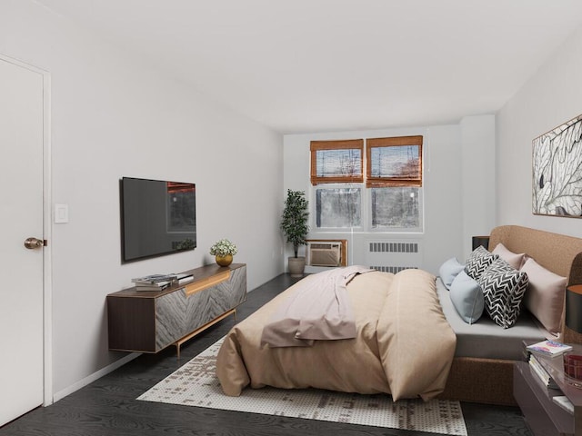 bedroom with radiator, wood finished floors, and a wall unit AC