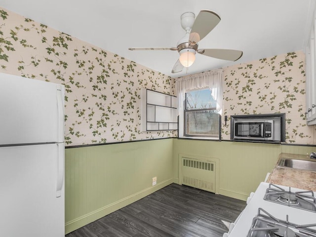 kitchen featuring a wainscoted wall, stainless steel microwave, freestanding refrigerator, radiator, and wallpapered walls