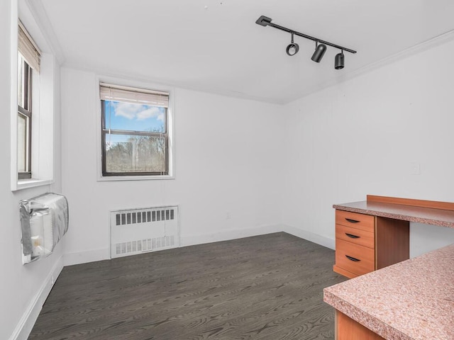 interior space with baseboards, radiator, dark wood finished floors, and rail lighting