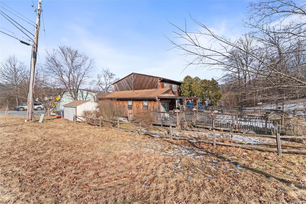 rear view of house with an outbuilding, a storage unit, and fence