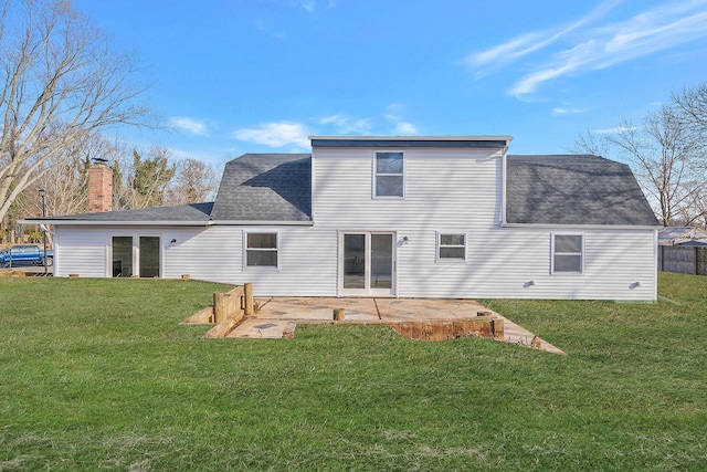 back of property with a patio area, a lawn, and roof with shingles