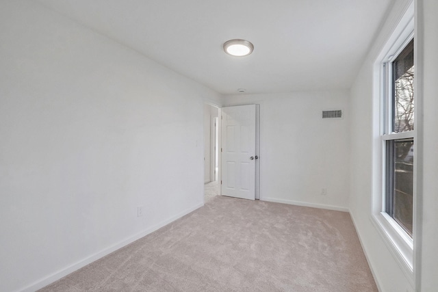 empty room featuring light carpet, visible vents, and baseboards