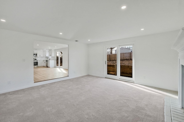 spare room featuring recessed lighting, plenty of natural light, light colored carpet, and baseboards