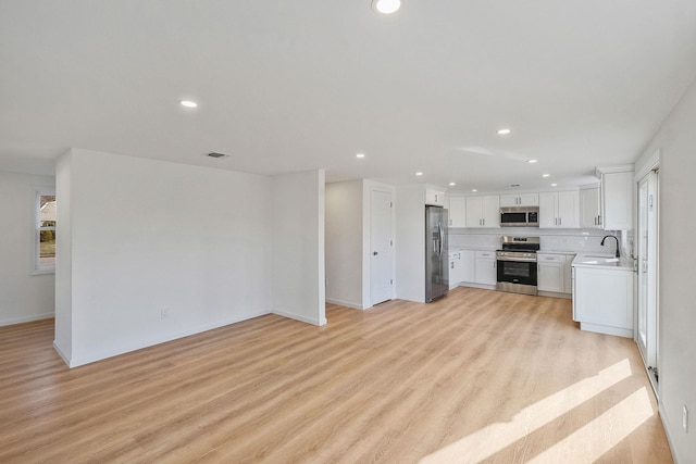 kitchen with recessed lighting, stainless steel appliances, open floor plan, and light wood-style flooring