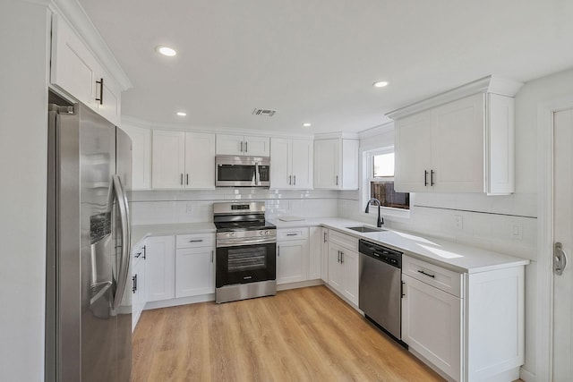 kitchen with visible vents, light wood-style flooring, a sink, appliances with stainless steel finishes, and white cabinetry