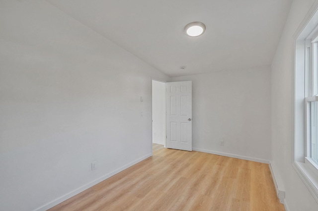 unfurnished room with baseboards and light wood-style floors