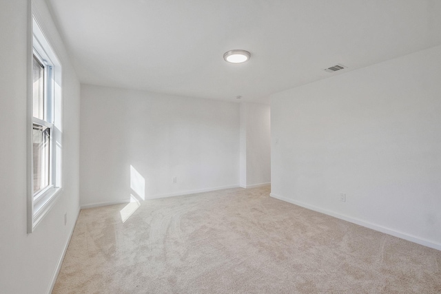 unfurnished room featuring visible vents, baseboards, and light colored carpet