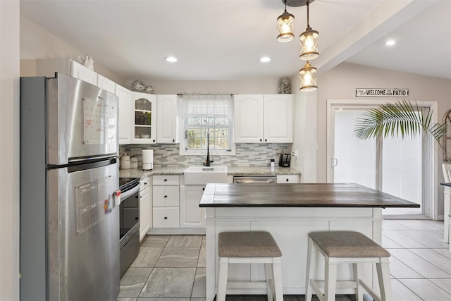 kitchen featuring a sink, decorative backsplash, vaulted ceiling, appliances with stainless steel finishes, and white cabinetry