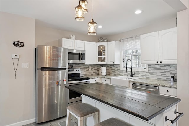 kitchen with a sink, a kitchen bar, backsplash, and appliances with stainless steel finishes