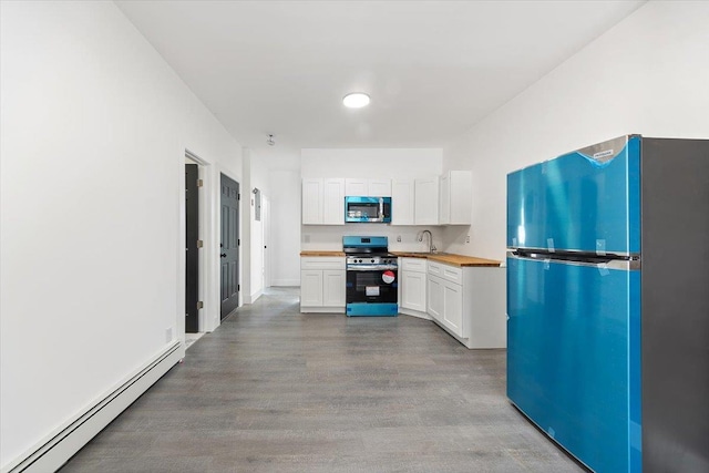 kitchen with wood finished floors, appliances with stainless steel finishes, white cabinetry, and a baseboard radiator