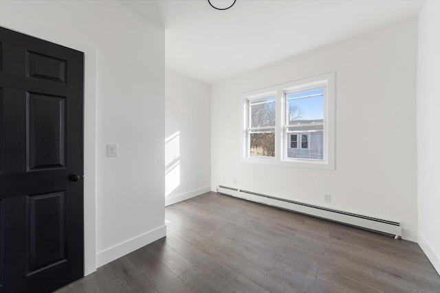 spare room with baseboards, baseboard heating, and dark wood finished floors