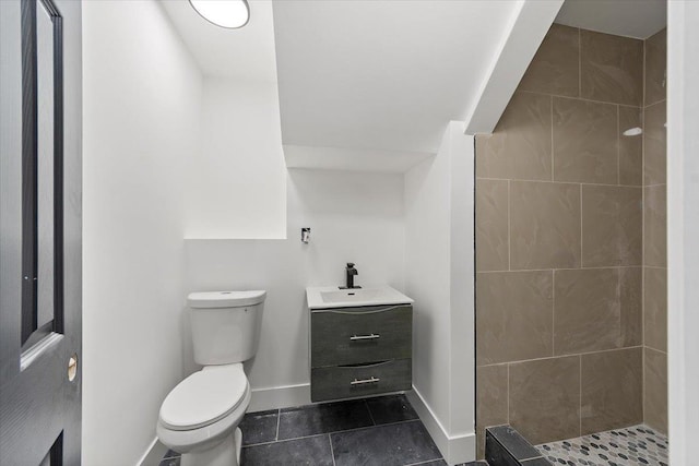 full bath with tile patterned floors, toilet, tiled shower, baseboards, and vanity