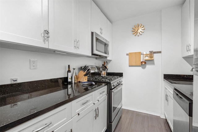333 Bronx River Rd Unit 123, Yonkers, NY 10704 - kitchen with stainless steel appliances, white cabinets, dark stone counters, wood finished floors, and baseboards