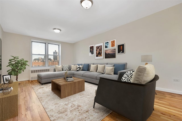 living room featuring light wood-style flooring, radiator heating unit, and baseboards