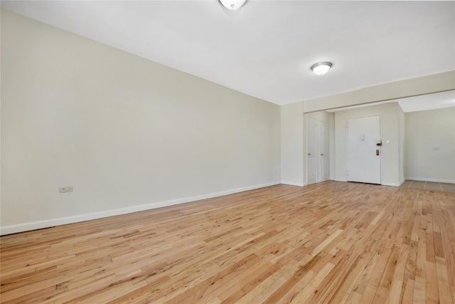 spare room featuring baseboards and light wood-style floors