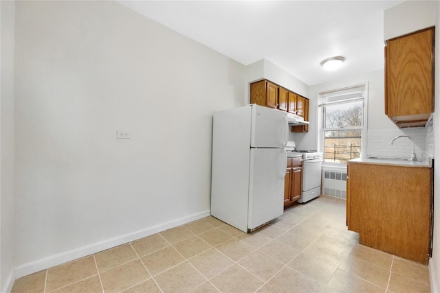 kitchen with white appliances, brown cabinets, light countertops, under cabinet range hood, and tasteful backsplash