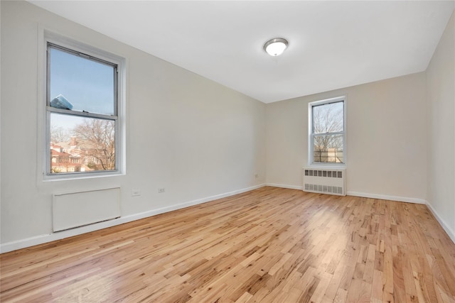 spare room with radiator heating unit, wood finished floors, and baseboards