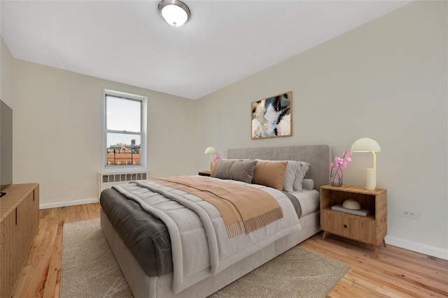 bedroom featuring light wood-style floors, baseboards, and radiator