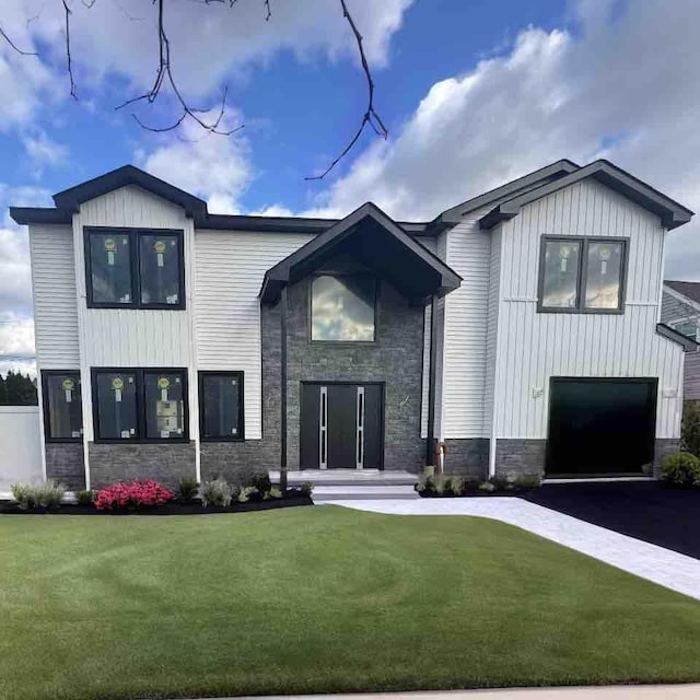 modern farmhouse with a front lawn, a garage, stone siding, aphalt driveway, and board and batten siding