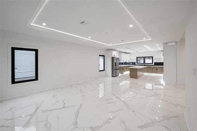 empty room featuring visible vents, baseboards, a tray ceiling, recessed lighting, and marble finish floor