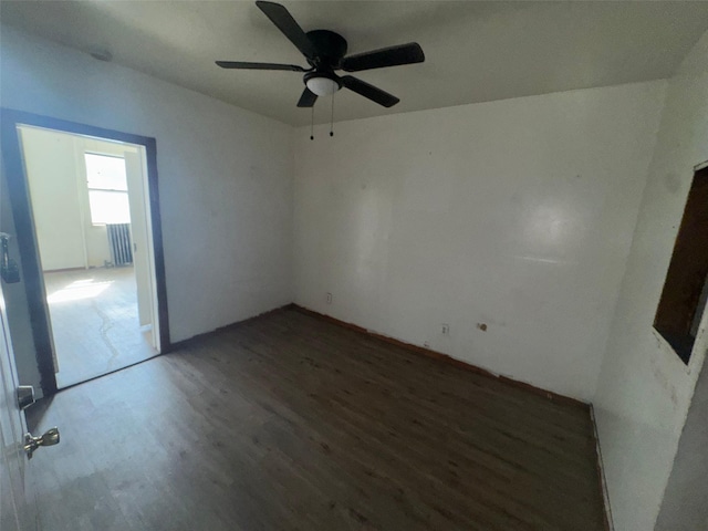 unfurnished room with radiator, wood finished floors, and a ceiling fan