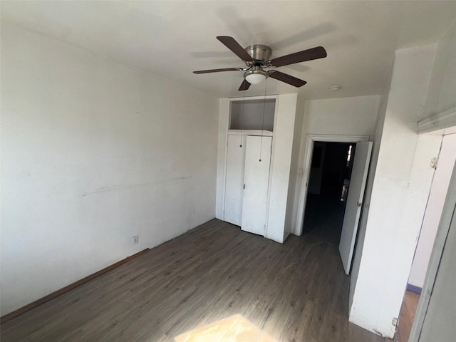 unfurnished bedroom with dark wood-style floors, a closet, and ceiling fan