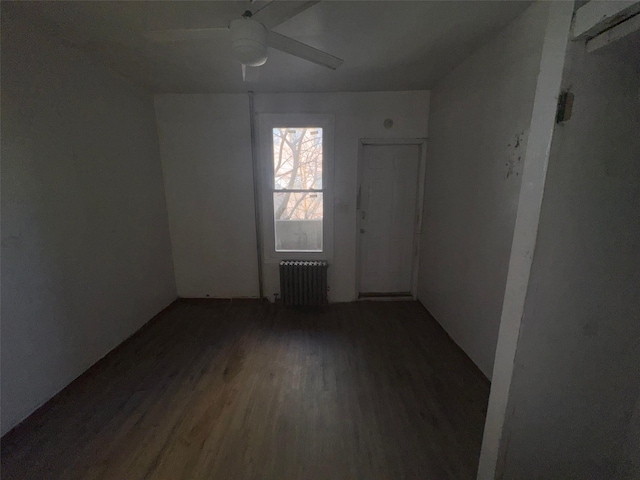 unfurnished room with a ceiling fan, radiator heating unit, and wood finished floors