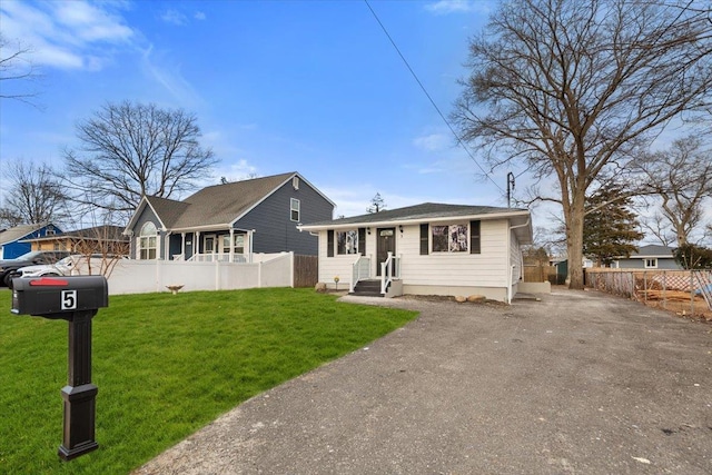 bungalow-style home featuring a front yard, fence, and driveway