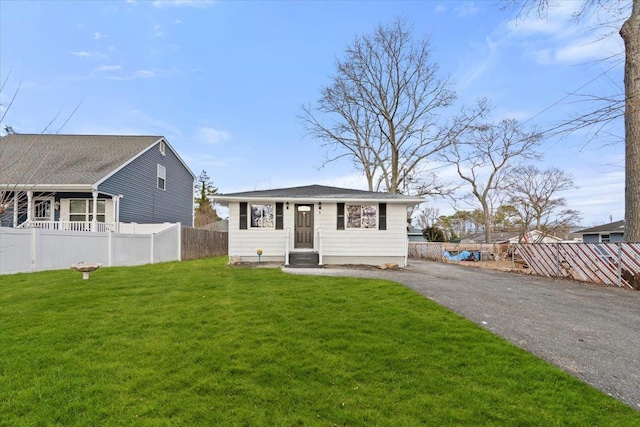 bungalow-style home featuring driveway, a front lawn, and fence