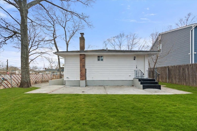 rear view of property featuring a patio area, a yard, a chimney, and fence