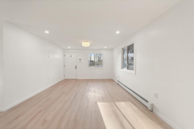 unfurnished room with recessed lighting, a baseboard heating unit, baseboards, and light wood-style floors