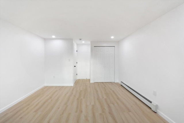 spare room with recessed lighting, a baseboard heating unit, baseboards, and light wood-style floors