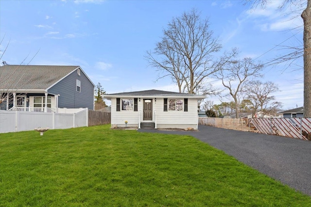 bungalow-style home featuring driveway, entry steps, a front lawn, and fence