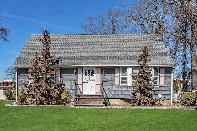 view of front of house with entry steps, a chimney, a front yard, and a shingled roof