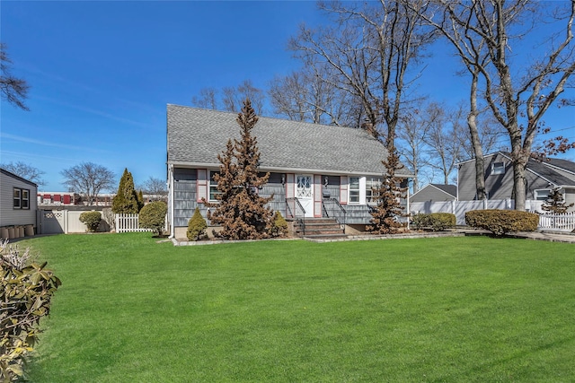 view of front of property featuring roof with shingles, a front lawn, and fence