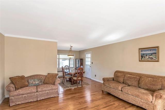 living area with baseboards, wood finished floors, and crown molding