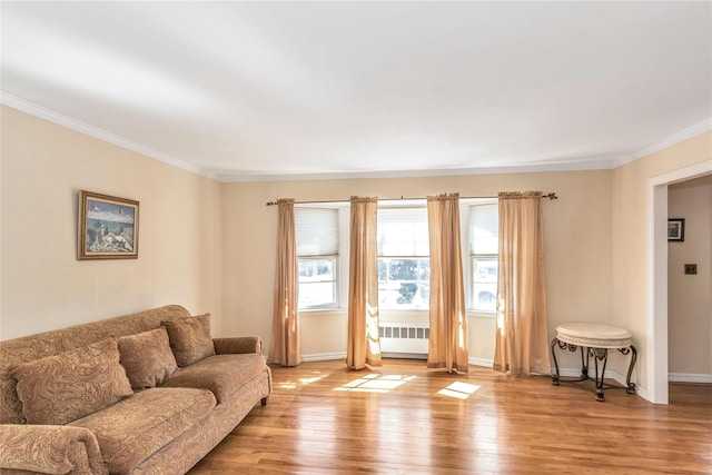 living area featuring radiator heating unit, baseboards, light wood finished floors, and ornamental molding