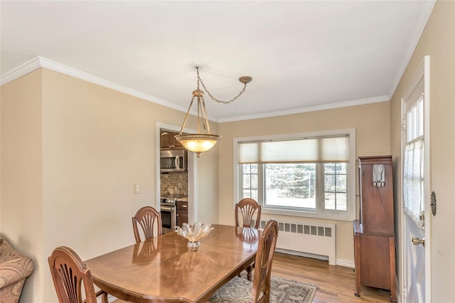 dining area with crown molding, light wood-style flooring, and radiator