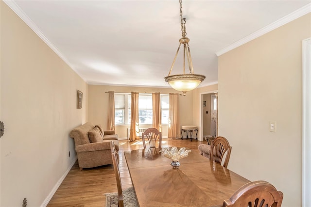 dining space with light wood-style floors, baseboards, and ornamental molding