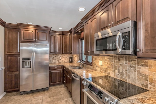 kitchen featuring dark brown cabinets, backsplash, light stone counters, stainless steel appliances, and a sink