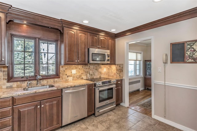 kitchen featuring radiator, a sink, stainless steel appliances, crown molding, and tasteful backsplash