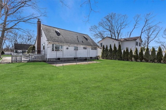 rear view of house featuring a yard, a chimney, and fence