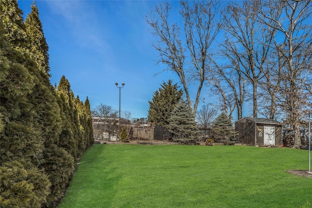 view of yard with an outbuilding, a fenced backyard, and a shed