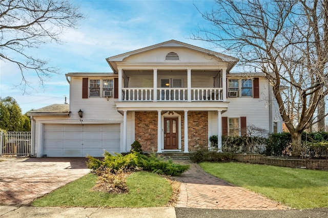 view of front facade with a balcony, fence, an attached garage, decorative driveway, and brick siding