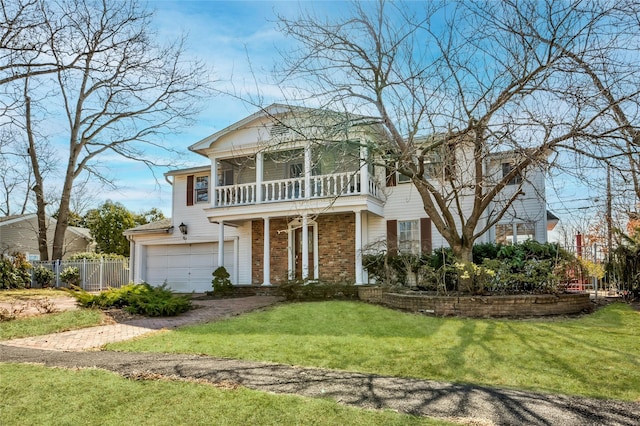 greek revival inspired property with a balcony, fence, a front yard, a garage, and brick siding