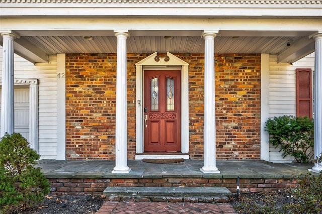 property entrance featuring brick siding and covered porch