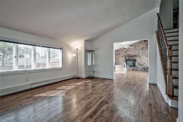 unfurnished living room with stairway, baseboard heating, a brick fireplace, and hardwood / wood-style flooring